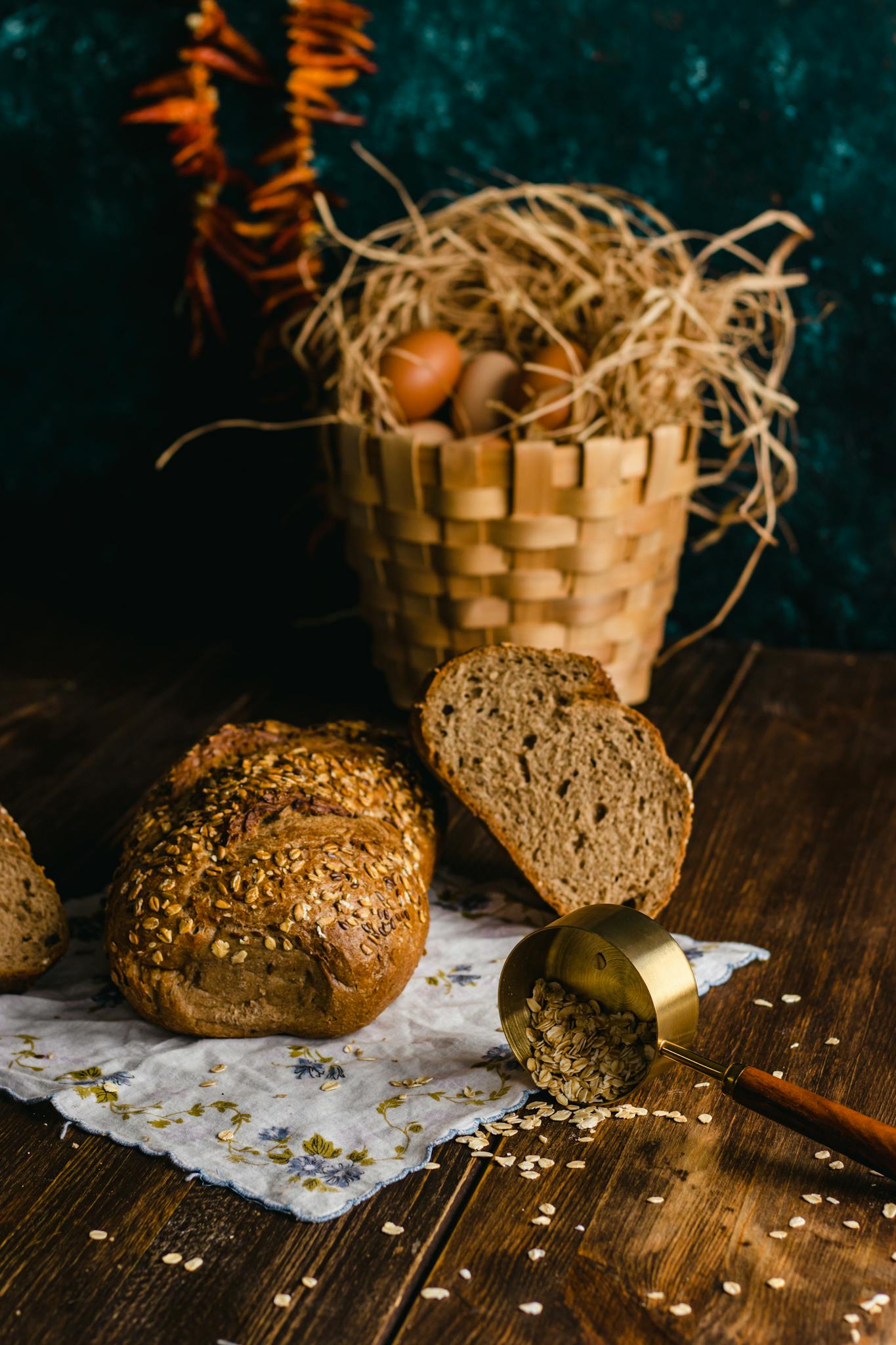 Artisan bread with oats and basket of eggs on rustic wooden surface.
